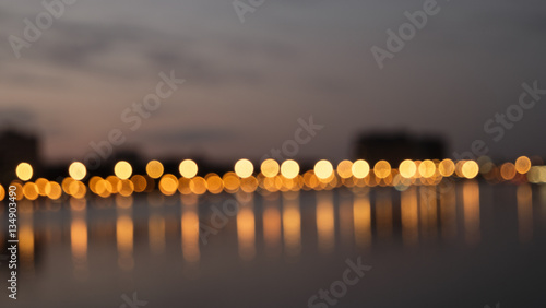 Fotografia, Obraz Bokeh night lights blurry abstract backgroun og city waterfront in a night