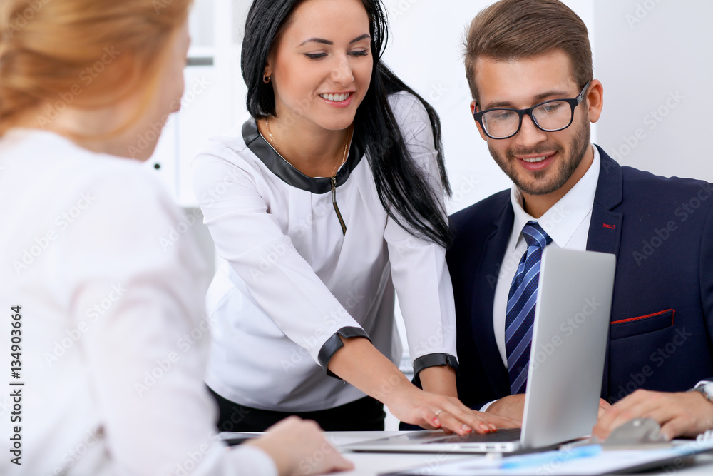 Business people at a meeting in the office. Focus on woman pointing into laptop Business people at a meeting in the office. Focus on woman pointing into laptop