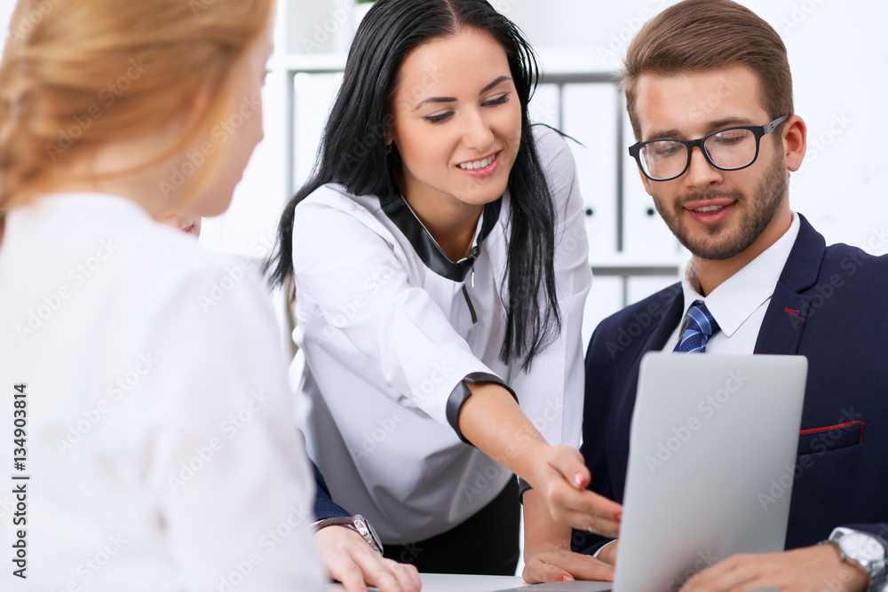 Business people at a meeting in the office. Focus on woman pointing into laptop Business people at a meeting in the office. Focus on woman pointing into laptop