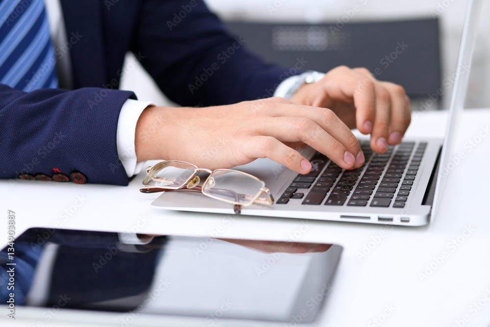 Young man working with laptop computer, man's hands on notebook, business person at workplace Young man working with laptop computer, man's hands on notebook, business person at workplace