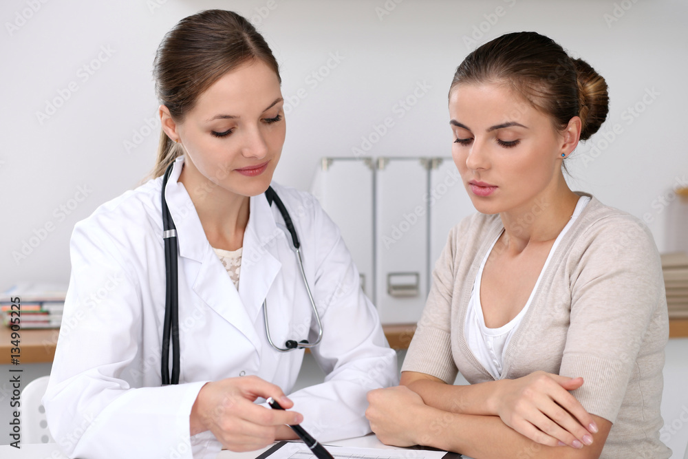 Doctor and patient sitting at the desk. Medicine and health care concept Doctor and patient sitting at the desk. Medicine and health care concept