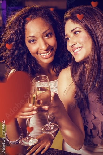 Composite image of happy young women having champagne