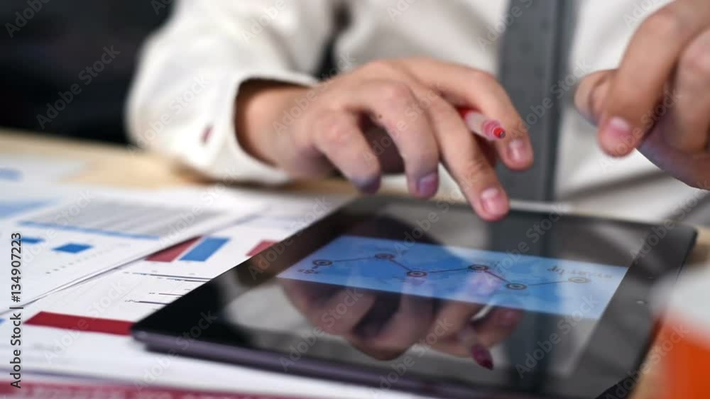 Businessman With Red Pen In Hand Using Touch Pad With With Finance Report Charts On Screen. Slow Motion Effect Businessman With Red Pen In Hand Using Touch Pad With With Finance Report Charts On Screen. Slow Motion Effect
