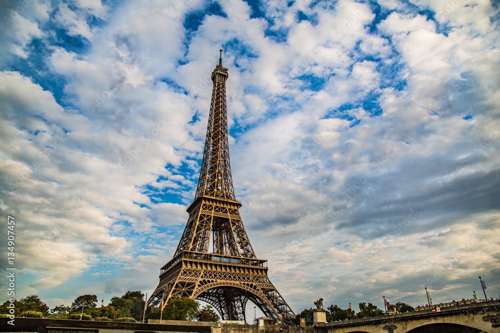 Fototapeta premium Eiffel Tower set against a cloudy blue sky in Paris, France