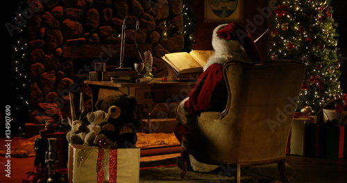 Santa Claus works at his desk, surrounded by Christmas decorations