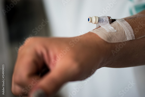 Cannula in right arm of a caucasian female held down by tape as a surgical aid to administer drugs   IV Intravenous drip   take blood from a patient inserted into a vein in hospital soft focus on hand