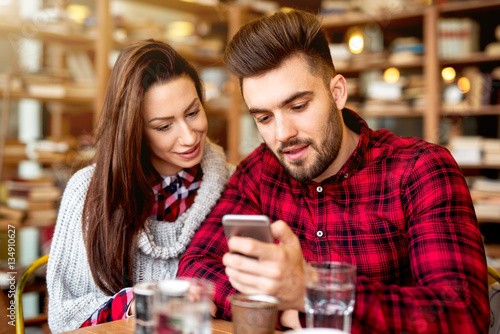 Couple at restaurant looking at smart phone.