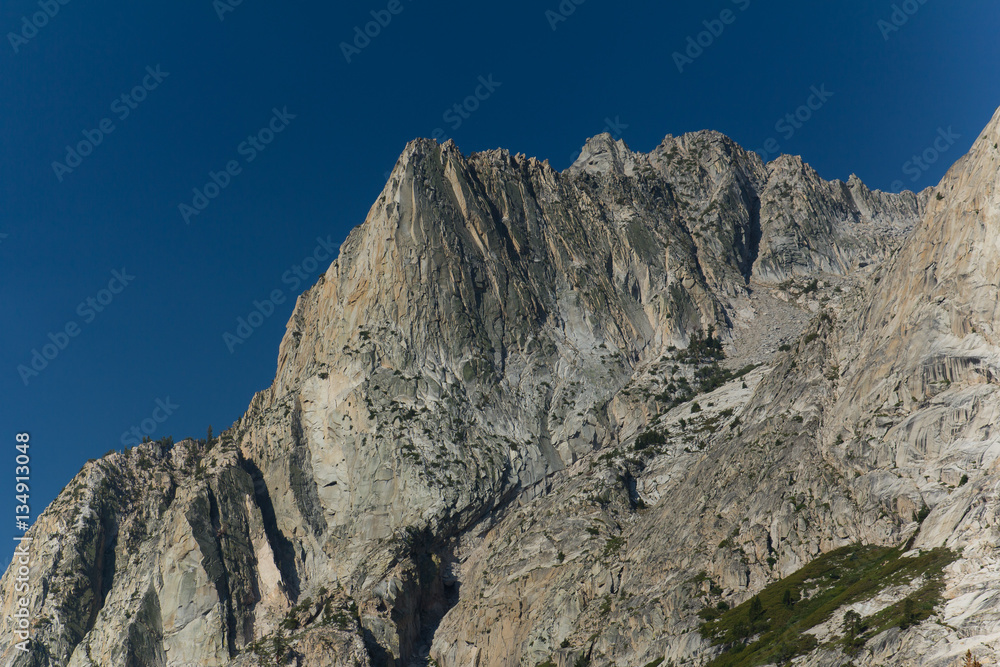 Towering granite peaks rise above a deep forested alpine valley in California's high sierra Towering granite peaks rise above a deep forested alpine valley in California's high sierra