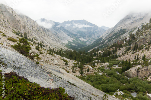 Towering granite peaks rise above a deep forested alpine valley in California's high sierra