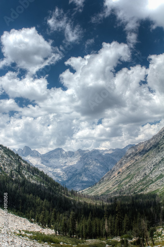Fluffy clouds float over a deep glacially carved valley in the high sierra