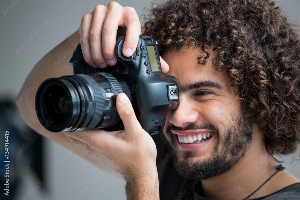 Fototapeta premium Male photographer with digital camera in studio
