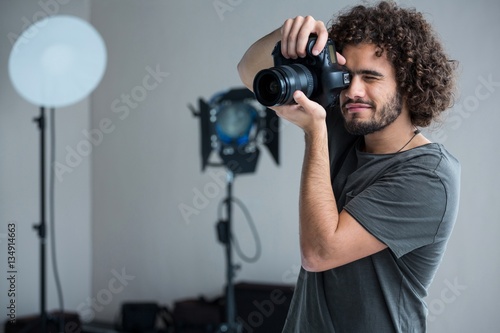 Happy male photographer with digital camera in studio photo