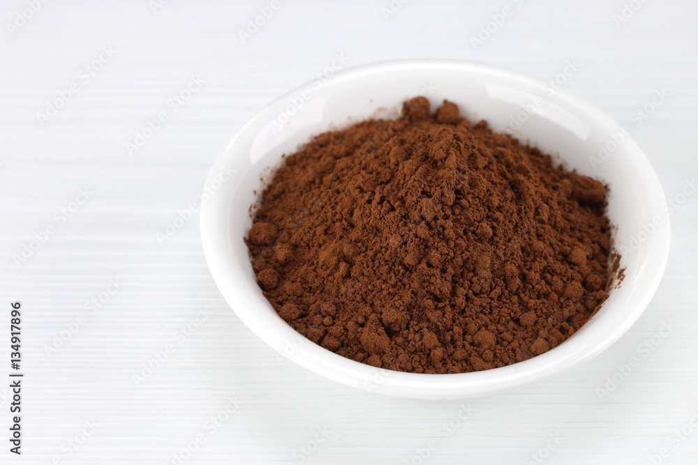 Cocoa powder in white bowl over wooden background Cocoa powder in white bowl over wooden background