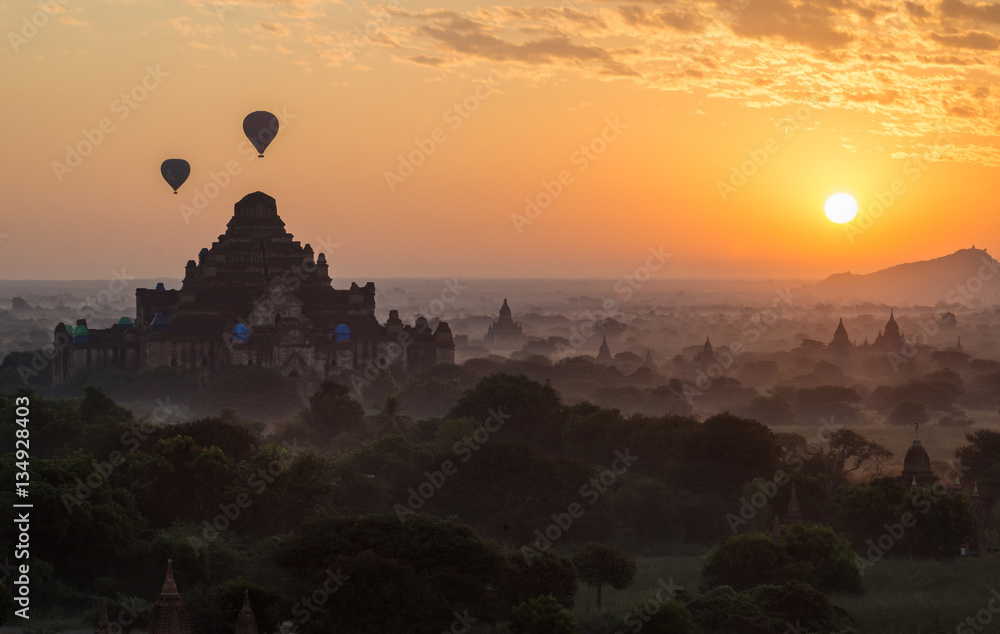 Hot air balloons fly over the Dhammayangyi temple the largest temple in Bagan plains during the morning sunrise in Myanmar.