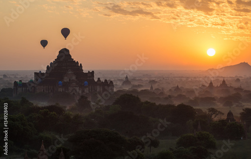 Hot air balloons fly over the Dhammayangyi temple the largest temple in Bagan plains during the morning sunrise in Myanmar.