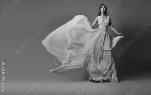 Young model posing in elegant long dress fluttering in the wind