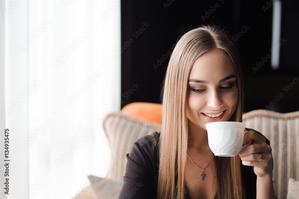 Young woman drinking coffee in a cafe and using a mobile phone Young woman drinking coffee in a cafe and using a mobile phone
