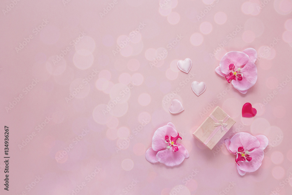 Background with gift box, orchid flowers and hearts on a pink.