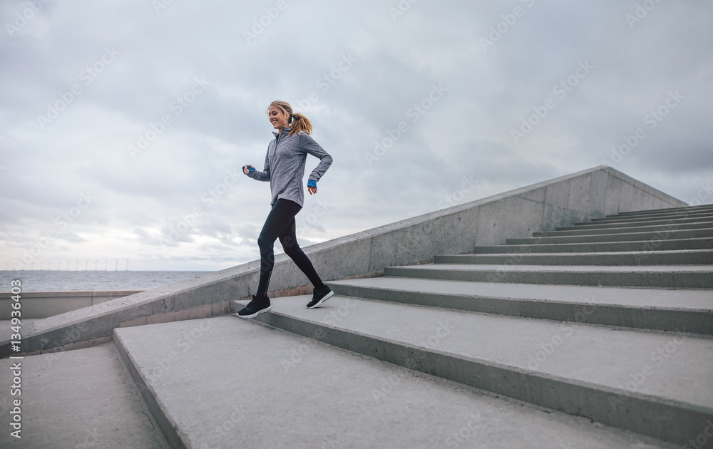 Healthy young woman running down on steps