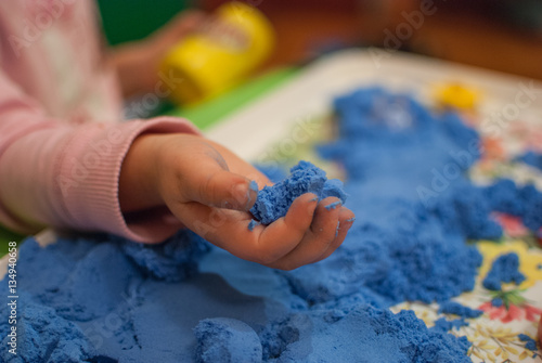 Child hand holding blue magic sand