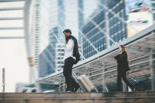 Businessman and businesswoman dragging a suitcase.