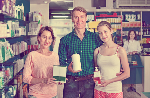 Smiling parents with girl teenager holding drug store goods
