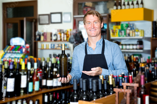 Male seller with wine bottle in hands