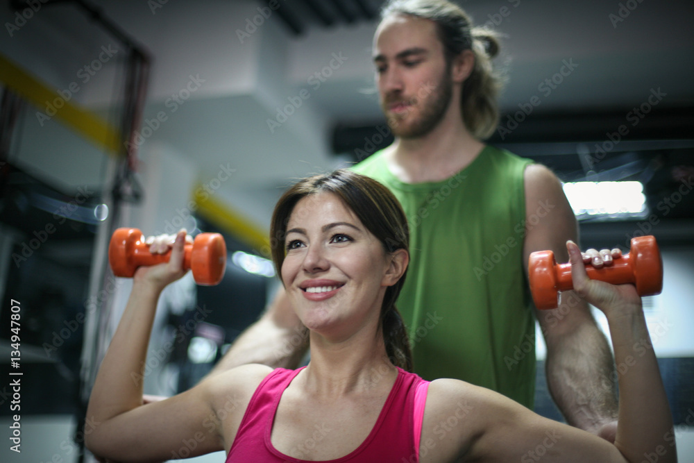 Fototapeta premium Personal trainer training his client in the gym.