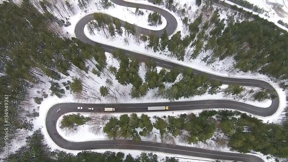 Aerial flight over high mountain road pass in winter , with dangerous steep turns for vehicle traffic Aerial flight over high mountain road pass in winter , with dangerous steep turns for vehicle traffic