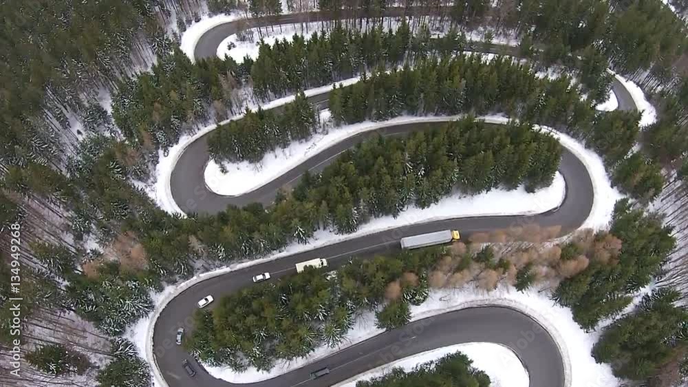 Trucks and cars slowly traversing dangerous bends and turns of a high mountain road pass , in winter time conditions, aerial view Trucks and cars slowly traversing dangerous bends and turns of a high mountain road pass , in winter time conditions, aerial view