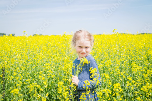 happy girl on blooming rapeseed field in summer