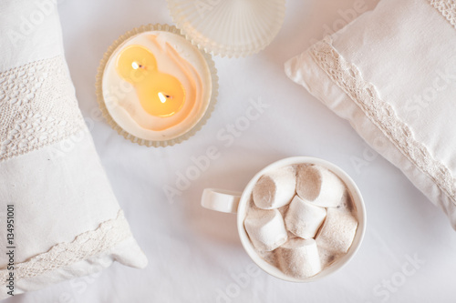 White cup of hot cocoa with marshmallows on white wooden backgro photo