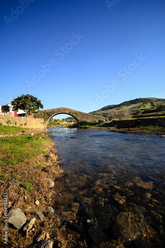 Old Roman bridge across small brook, village of Cheleiros, Portugal photo