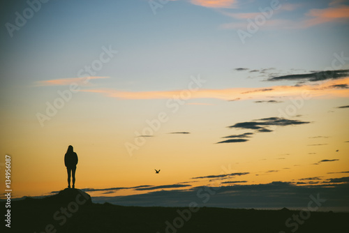 Lonely girl watching sunset in most westerly point of Europe in Iceland