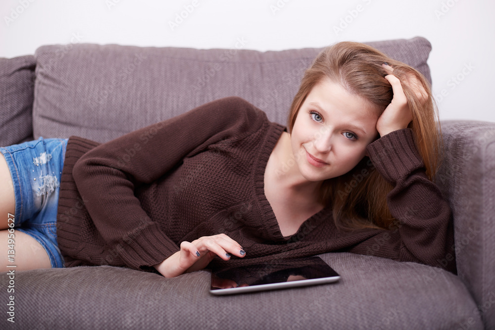 Happy young woman with tablet pc laying on sofa Happy young woman with tablet pc laying on sofa