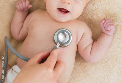 Dostor with stethoscope checking baby photo