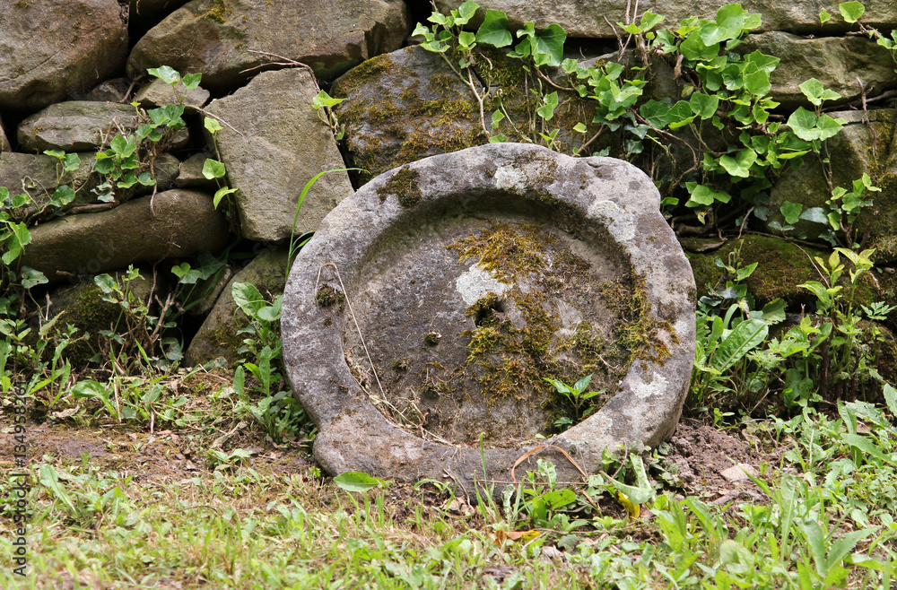 Old millstone on a background of stone wall, Etar, Bulgaria Old millstone on a background of stone wall, Etar, Bulgaria