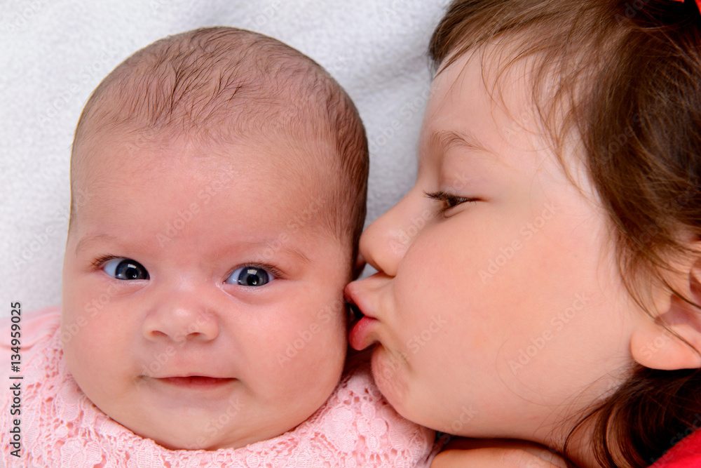 little girl kissing her baby- siste little girl kissing her baby- siste