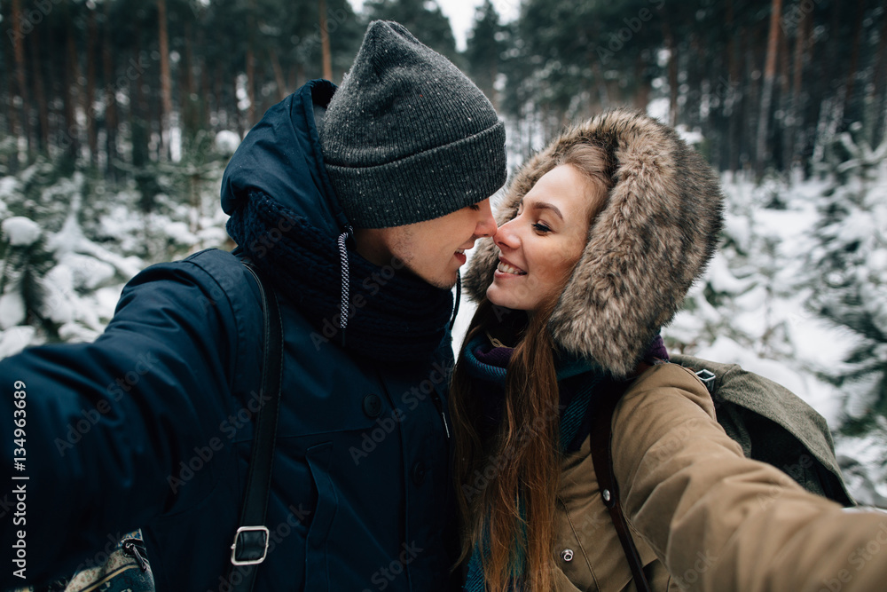 Happy couple of travelers in love take selfie in winter forest Happy couple of travelers in love take selfie in winter forest