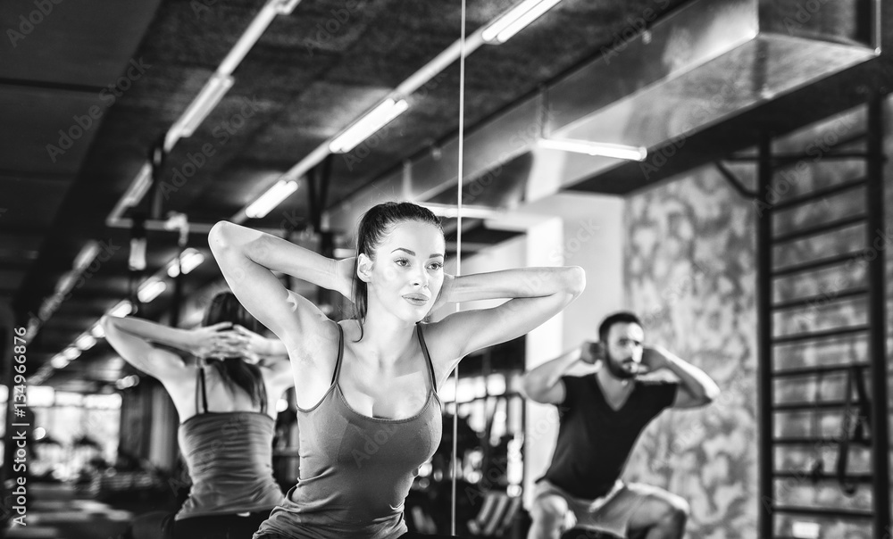Attractive athletes doing squats in fitness studio. Black and white photo.
Attractive athletes doing squats in fitness studio. Black and white photo.