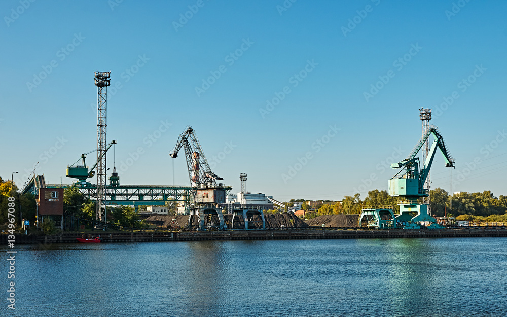 Obraz premium cranes on the quay of the river under blue sky