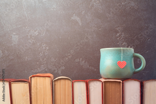 Valentines day concept with tea cup on books over blackboard background