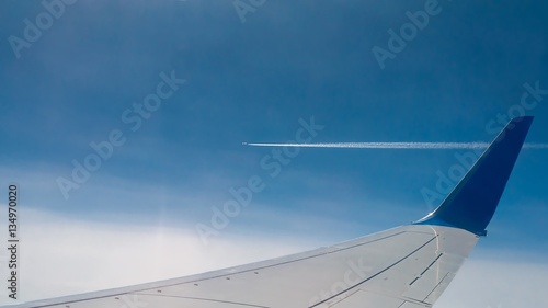 Wing aircraft against the sky and other aircraft. Background. View from the plane window. Condensation, vapor trail from an airplane.