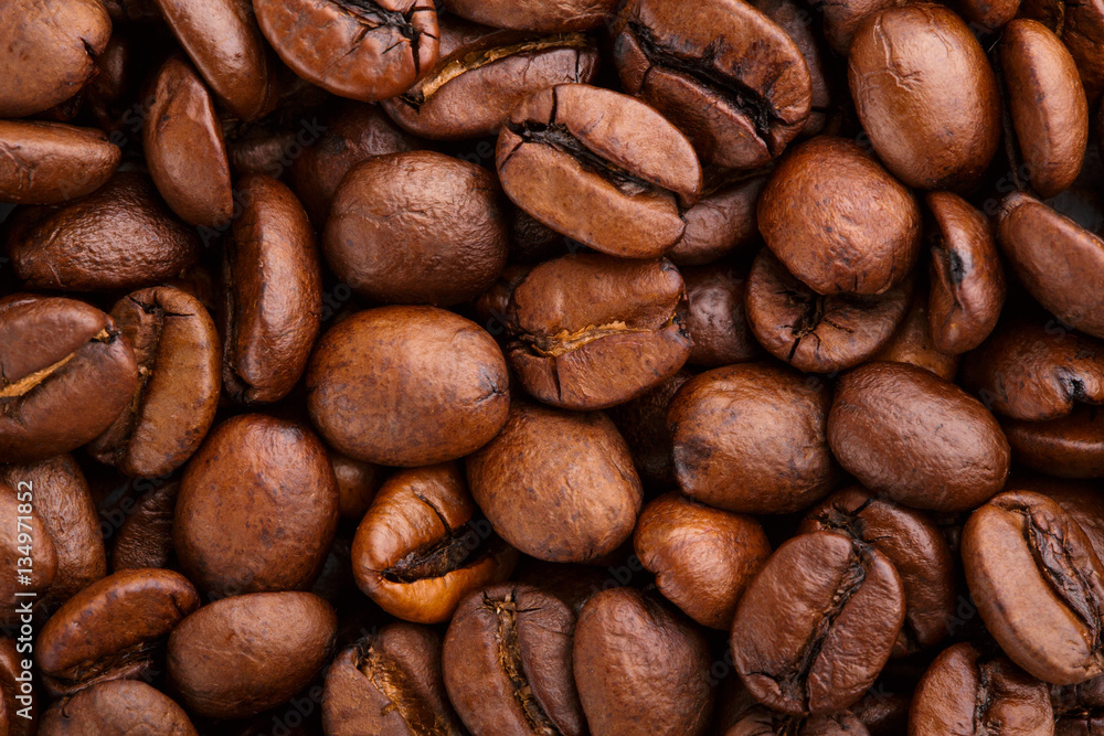 Naklejka premium roasted coffee beans isolated in white background. Roasted coffee beans background close up. Coffee beans pile from top on white background with copy space for text. Good morning.
