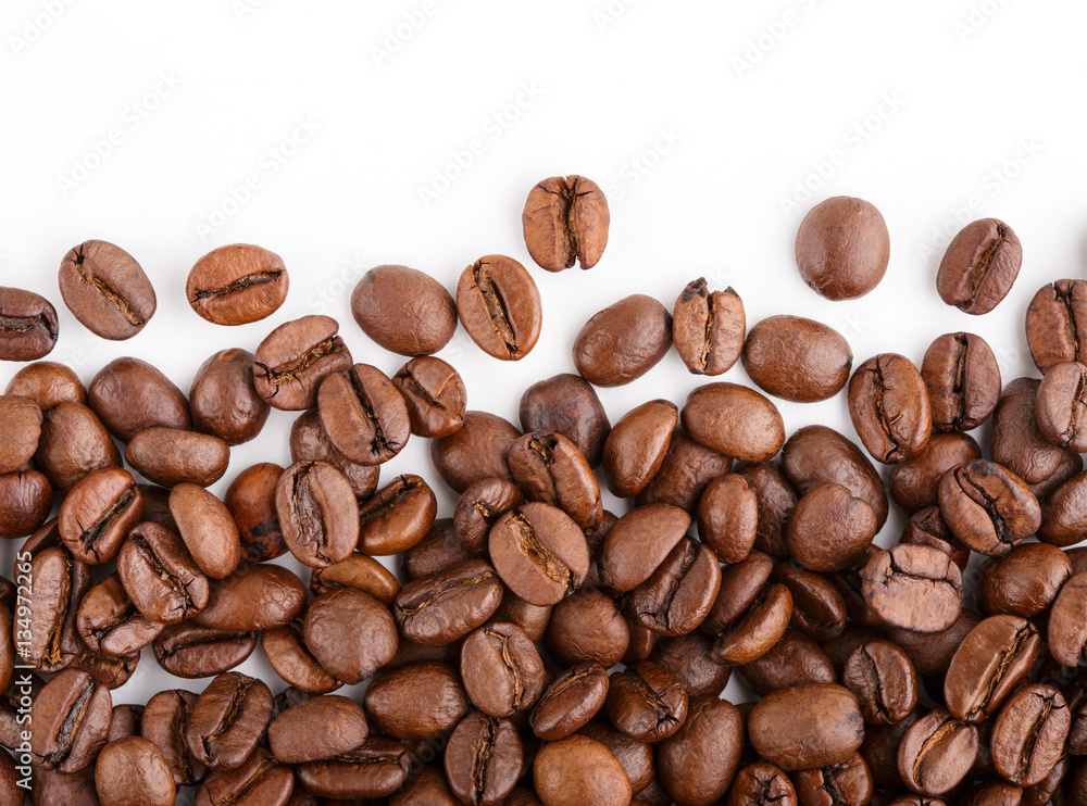 Naklejka premium roasted coffee beans isolated in white background. Roasted coffee beans background close up. Coffee beans pile from top on white background with copy space for text. Good morning.