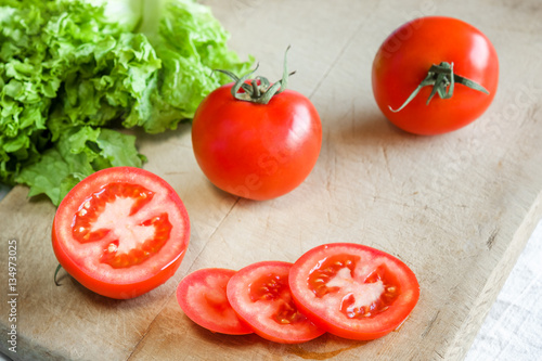 Tomatoes and lettuce on a wooden background.