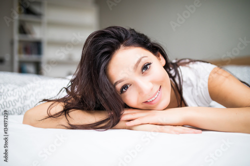 Young beautiful woman lying in bed at home