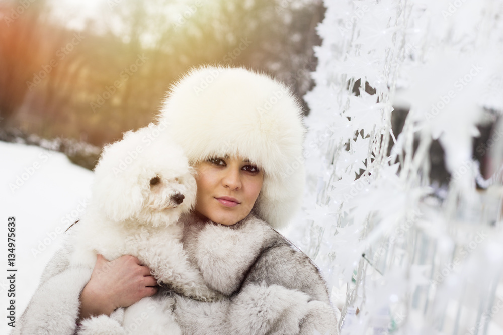 Beautiful woman in the winter time with her dog. Woman wearing a winter coat. Lens flare in the background. Beautiful woman in the winter time with her dog. Woman wearing a winter coat. Lens flare in the background.
