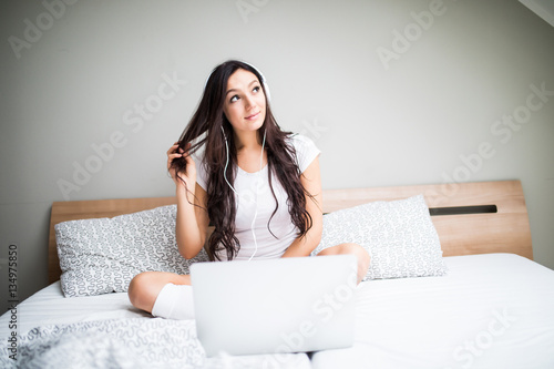 Beautiful young woman listening to music in headphones at home