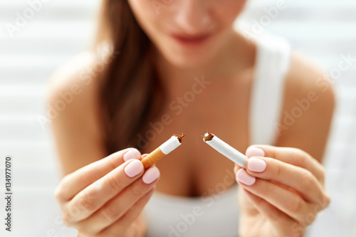 Woman Hand Showing Broken Cigarette. Unhealthy Lifestyle photo
